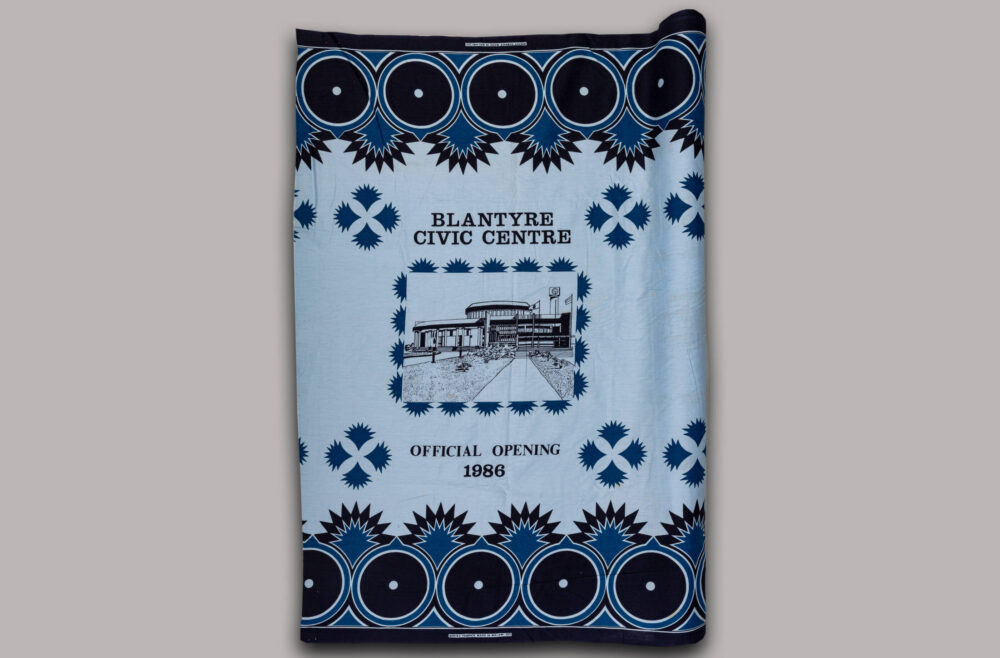 Stoff in Blautönen mit verschiedenen Ornamenten und einer Aufschrift zur Eröffnung des Blantyre civic centre 1986.