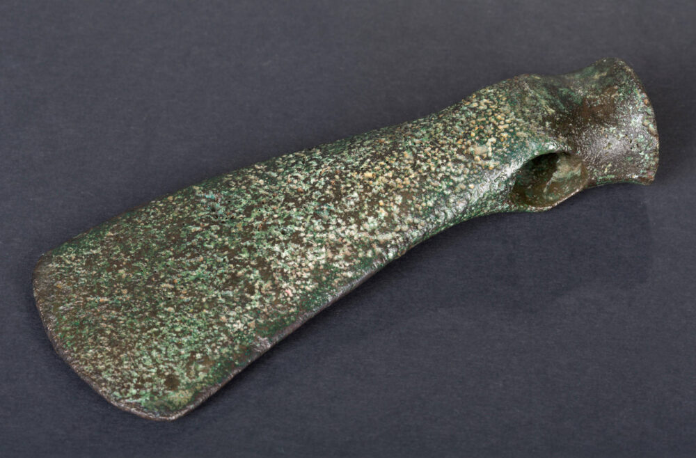 Grünlich angelaufener Kopf einer kupfernen Streitaxt.