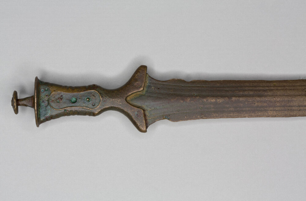 Detailfoto eines Vollgriffschwertes aus Bronze, aufgenommen im Bereich des Knaufs bis zur Klinge.
