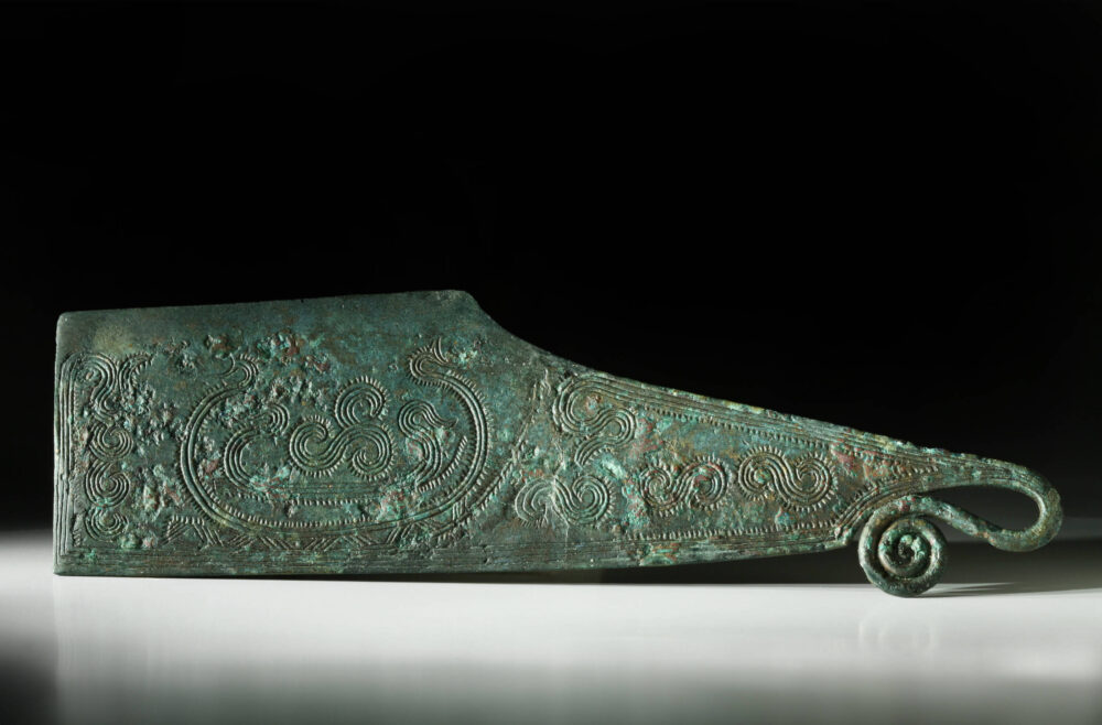 Ein spätbronzezeitliches grün angelaufenes Rasiermesser aus Bronze mit gravierten S-förmigen Verzierungen.