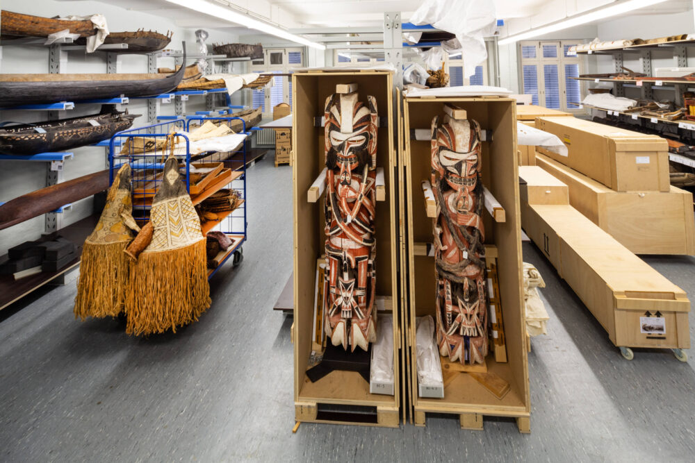 Blick ins ethnologische Depot mit Booten in den Wandregalen und zwei Kisten mit Malanganen im Vordergrund.