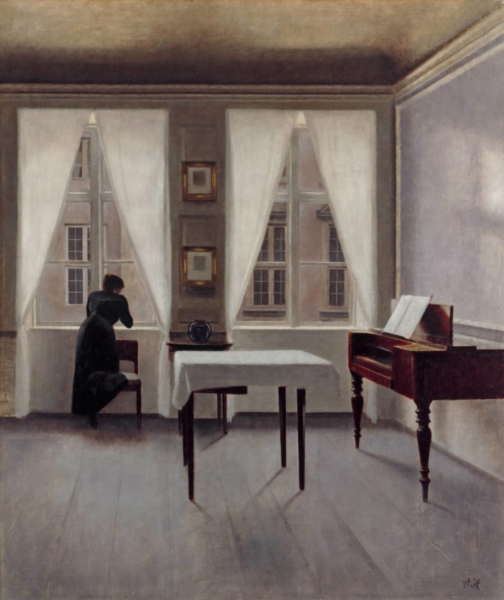 Gemälde des Malers Vilhelm Hammershøi, das ein Zimmer mit Tisch, Hammerklavier und einer nach draußen blickenden Frau zeigt.