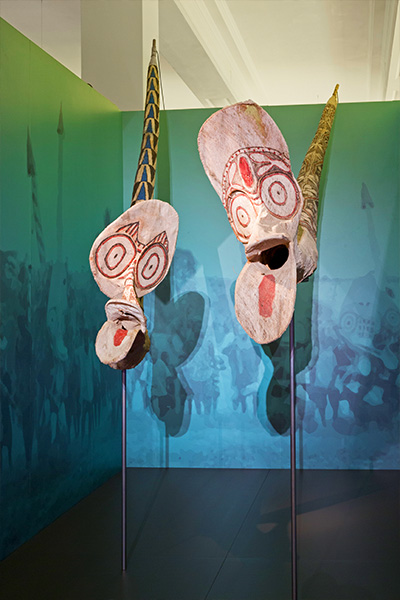 Zwei Tanzmasken mit großem Kopf, geöffnetem Maul und meterlangem Schwanz aus Rindenbast.