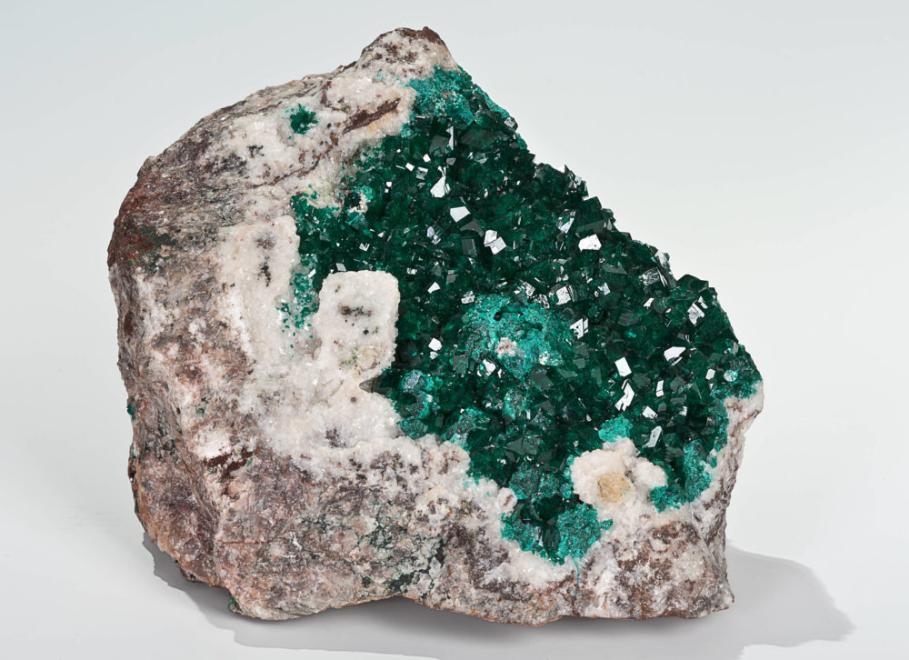 Ein innen dunkelgrüner und außen braun-melierter Kristall vor weißem Hintergrund