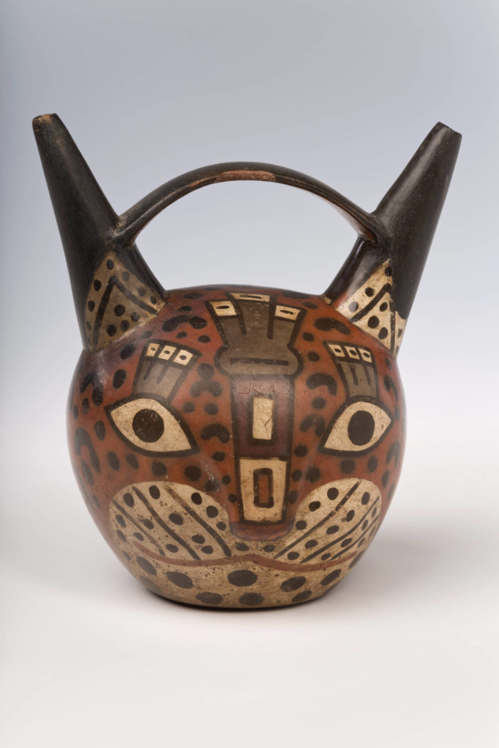 Peruanisches Gefäß in abstrakter Form und Bemalung eines Katzenkopfes.