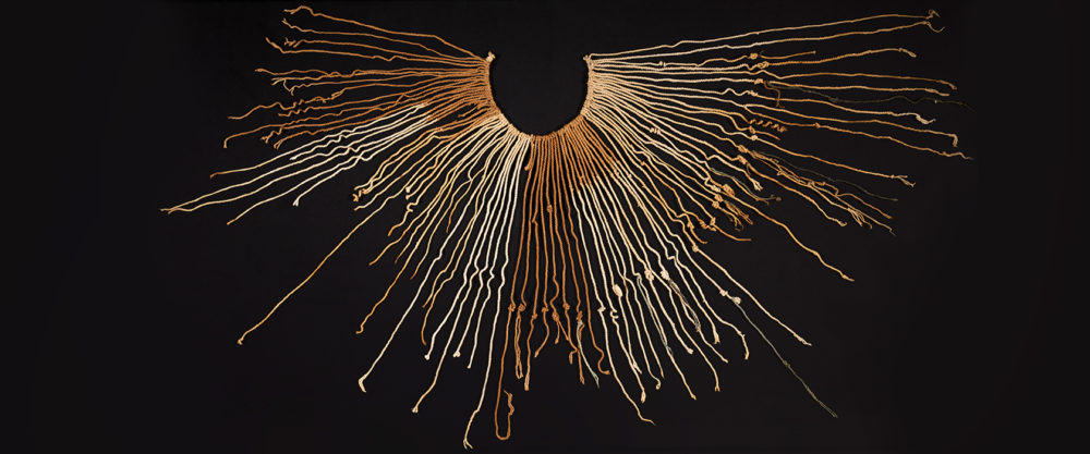 Ausgebreitete Quipu-Schnur der Inka in braun-beige-Tönen vor schwarzem Hintergrund.